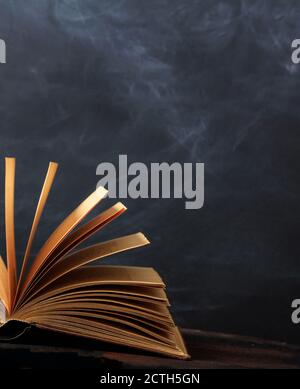 Old book opened on a wooden shelf, black board background. Law, history library shelf, vertical shot Stock Photo