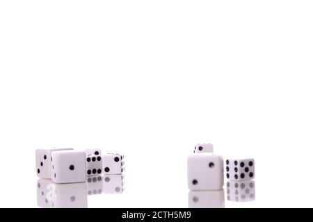 Scattered white dice of different sizes are reflected on table surface Stock Photo