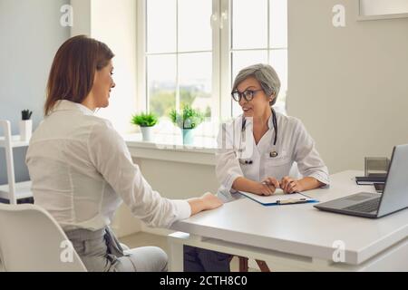 Senior woman doctor therapist consulting woman patient in medical clinic office during clinic