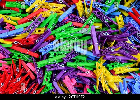 Multi-colored assortment of brightly colored plastic clothes pins scattered in a pile Stock Photo