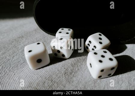 Five dice with different numbers and cup in the background Stock Photo