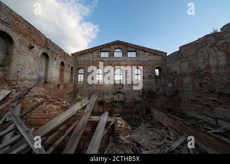 old ruined brick building, walls. Without a roof, under an open blue sky. piles of garbage inside Stock Photo