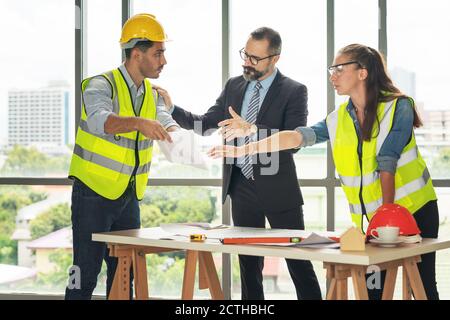 Team of multiethnic architects working on construction plans in meeting room. Engineers discussing on project in office. Mature businessman and woman Stock Photo