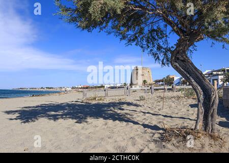 Torre Mozza beach in Salento, Apulia (Italy). The ruined watchtower overlooks the long beach of Torre Mozza with fine sand lapped by the clear water. Stock Photo