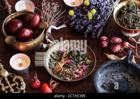 Wiccan witch altar with herb blend mix in brass dish, ready for incense burning. Background filled with dried lavender rose flowers, herbs, plants Stock Photo