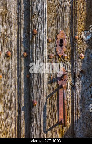Old metal handle on weathered oak church doors - Oradour-Saint-Genest, Haute-Vienne (87), France. Stock Photo