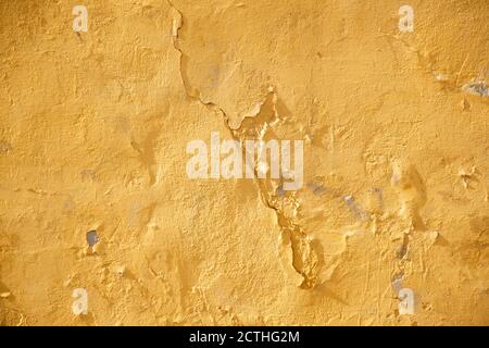 Yellow old scratched and cracked stucco wall on the facade of the back design blank Stock Photo