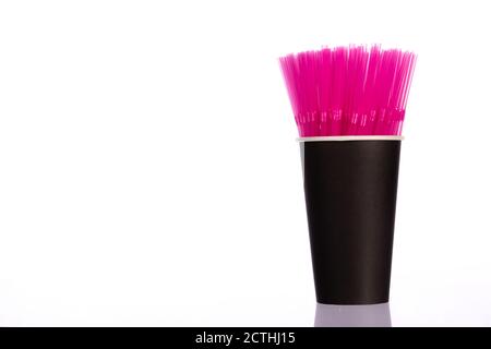Pink plastic straws in black paper cup isolated on white background. Copy space Stock Photo