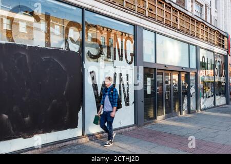 A young man walks past a closing down store on Camden High Street on an unusually warm late-September afternoon, London, UK Stock Photo
