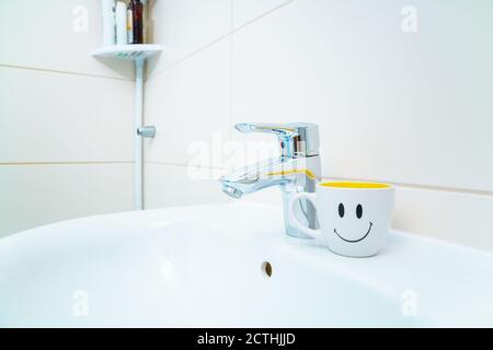 Bathroom sink and faucet with toothbrushes and soap dispenser Stock Photo -  Alamy