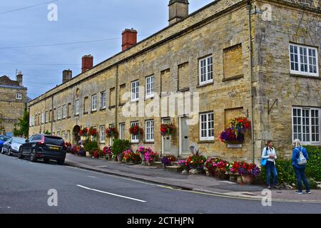 Pretty flowers outside old stone houses on Cecily Hill Cirencester. Some windows blocked up to avoid old 'window tax' from 18th & 19th century. Stock Photo