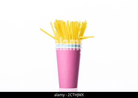 Yellow plastic straws in disposable colorful cups isolated on white background Stock Photo