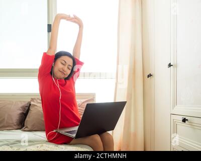 Asian woman Finished working in the bedroom by the laptop Stock Photo