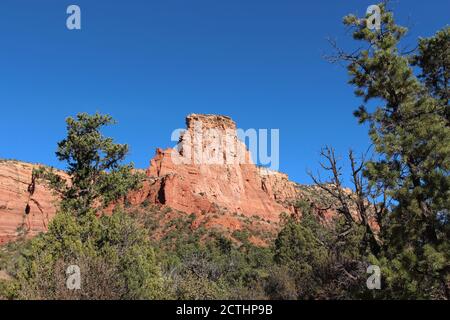 The red sandstone and white limestone mountains of Sedona lined with evergreens on the Courthouse Butte Loop Trail in Arizona, USA Stock Photo