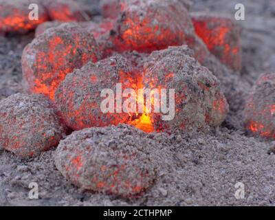 Orange glowing coal pieces with grey ashes Stock Photo