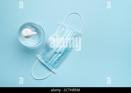 Surgical protective face mask with antibacterial gel on blue background Stock Photo