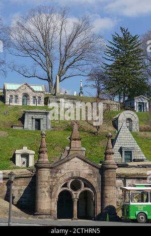 Brooklyn, New York: A trolley waits for passengers below obelisks and mausoleums on a hillside in a section of historic Green-Wood Cemetery. Stock Photo