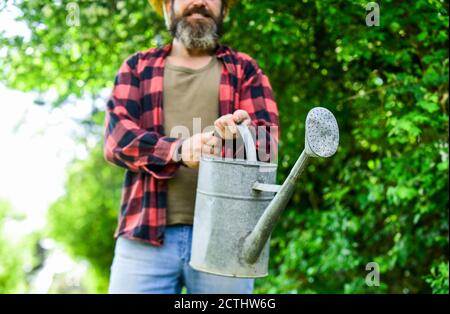 Man using a big watering can for planting. pour the water. man with watering can. gardening and watering plants. agriculture and tough work concept. Gardening or planting concept. Stock Photo