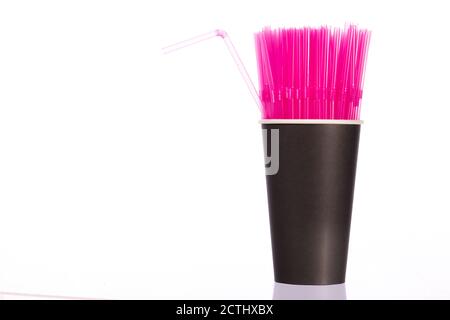 Bunch of pink plastic straws in black disposable biodegradable paper cup Stock Photo
