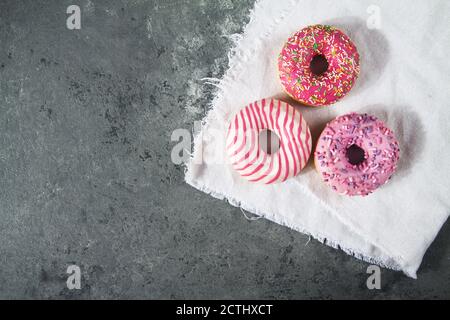 Baked sweet delicious donuts with pastry crumb on gray concrete background. Happy Donut Day. National Donut Day Poster. American delicacy food Stock Photo