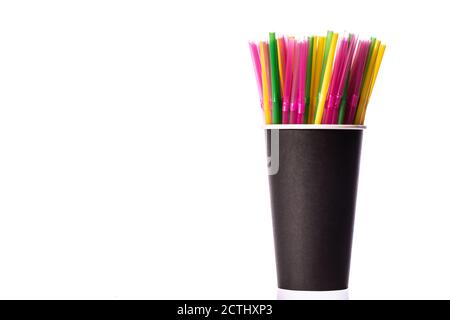 Multi-colored plastic straws in black paper glass isolated on white background Stock Photo