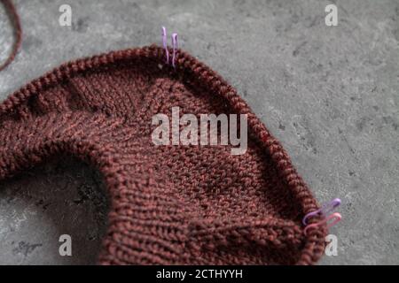 Brown sweater, knitting process, concrete background. Raglan needles. woolen weave threads. Stock Photo