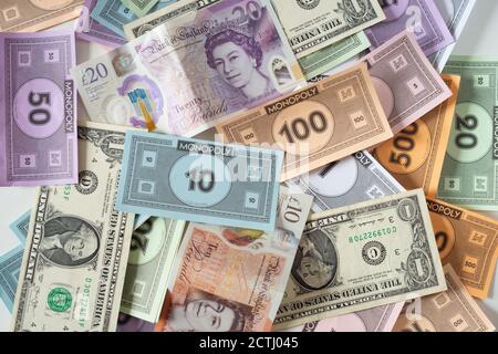 Banknotes in amongst monopoly money, a metaphor for inflation, debt, diminishing value, interest rates, lack of purchasing power, weak currency Stock Photo