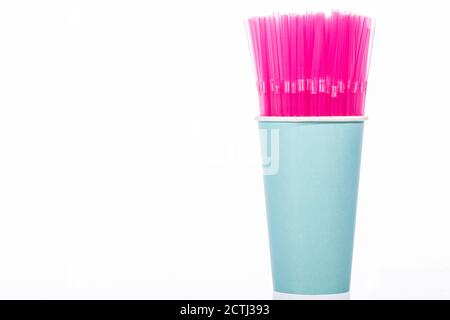 Pink plastic drinking straws in blue disposable cup isolated on white background Stock Photo