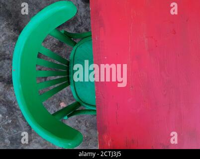 Red table background planks or texture of wooden planks, and bright green wooden chair Stock Photo