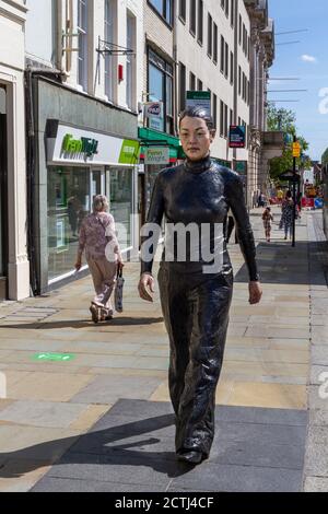 A woman walking along the street, one of a pair of bronze sculptures by Sean Henry, High Street, Colchester, Essex, UK. Stock Photo