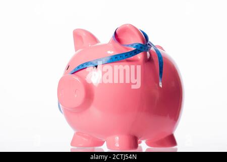 pink piggy bank with blue measuring tape tied around ears isolated on white Stock Photo