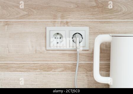 https://l450v.alamy.com/450v/2ctj5c0/white-electric-kettle-plugged-into-a-power-outlet-on-a-wall-into-a-kitchen-2ctj5c0.jpg