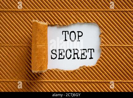 The words 'top secret' appearing behind torn brown paper. Business concept. Stock Photo