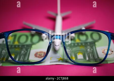 View on isolated eyeglasses with blurred plane and two hundred euro paper banknotes on pink backgound (focus on center of eyeglass frame) Stock Photo