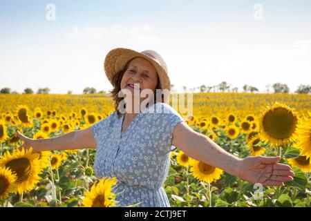 Portrait of a happy old woman in a sunflower field. Space for text. Stock Photo