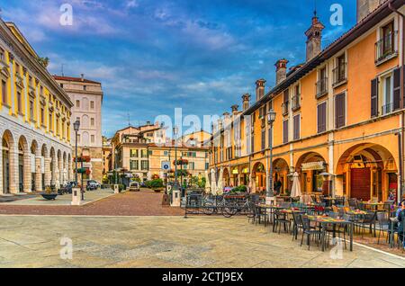 Typical italian buildings and tables of street restaurants on Piazza del Mercato Market square in Brescia city historical centre, evening twilight view, Italian street, Lombardy, Northern Italy Stock Photo