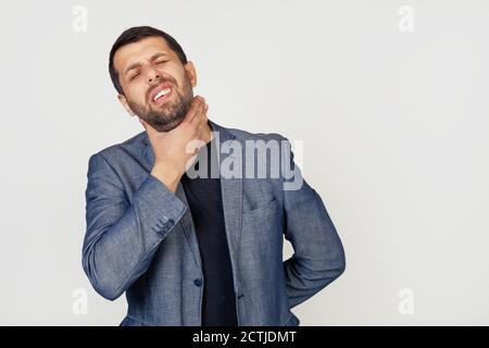 Young businessman man with beard touching painful neck, sore throat from flu, lump and infection. Portrait of a man on a gray background. Stock Photo
