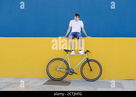Disabled young male bicyclist with prosthetic leg resting on colorful border Stock Photo