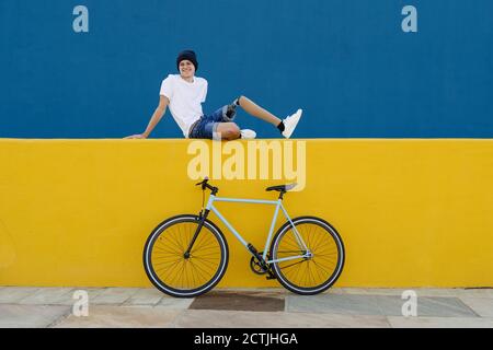 Disabled young male bicyclist with prosthetic leg resting on colorful border Stock Photo