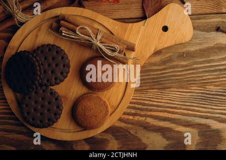 Chocolate chip cookies and cinnamon sticks on a tray. The concept of Thanksgiving, Christmas and Halloween. Baking on a wooden background. Stock Photo