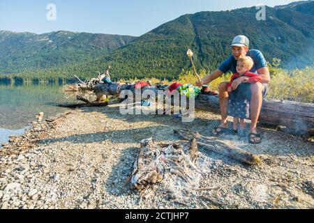Father and son roast marshmallows over fire during a father son trip Stock Photo