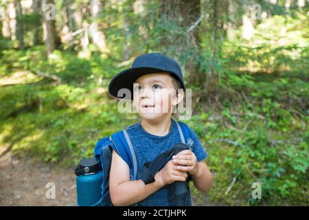 Portrait of young male hiker wearing backpack in forest. Stock Photo