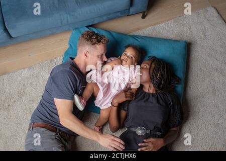 A biracial family laying on the floor with their daighter Stock Photo