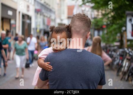 A father carrying his young daughter through streets of Europe Stock Photo