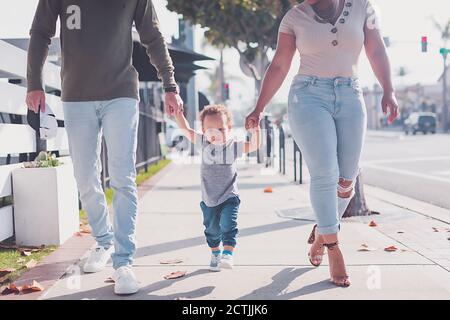 Family of three walking in Downtown, baby boy walking with parents Stock Photo