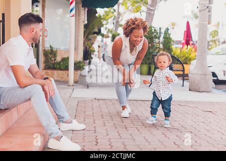 Interracial family playing with toddler on the sidewalk Stock Photo