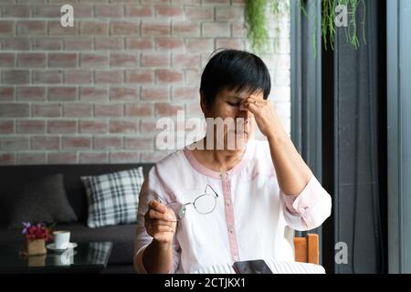 Old woman headache while using smartphone, healthcare concept Stock Photo