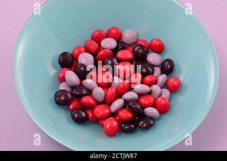 Strawberry, blackberry and raspberry fruit candies in blue bowl on lavender background Stock Photo