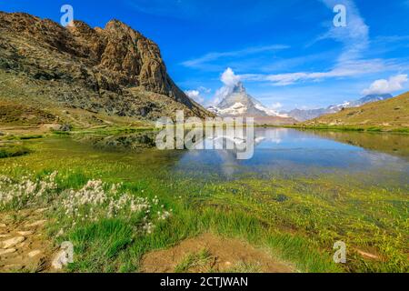 Alpine meadows around Riffelsee Lake with mirror of Mount Matterhorn and Swiss Alps. Zermatt, Canton of Valais, Switzerland. Riffelsee is located on Stock Photo