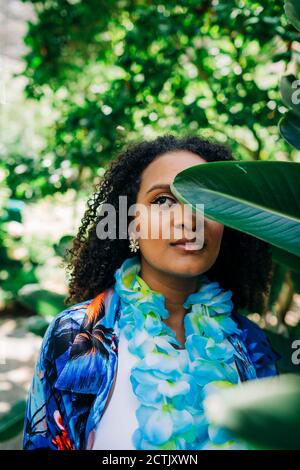 Young woman hiding behind leaf while standing at park Stock Photo